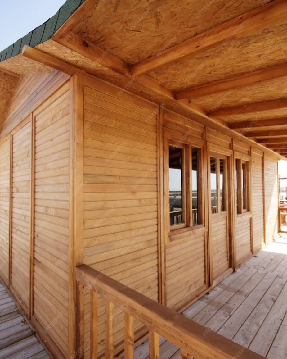Una casa de madera con techo verde y muchas ventanas.