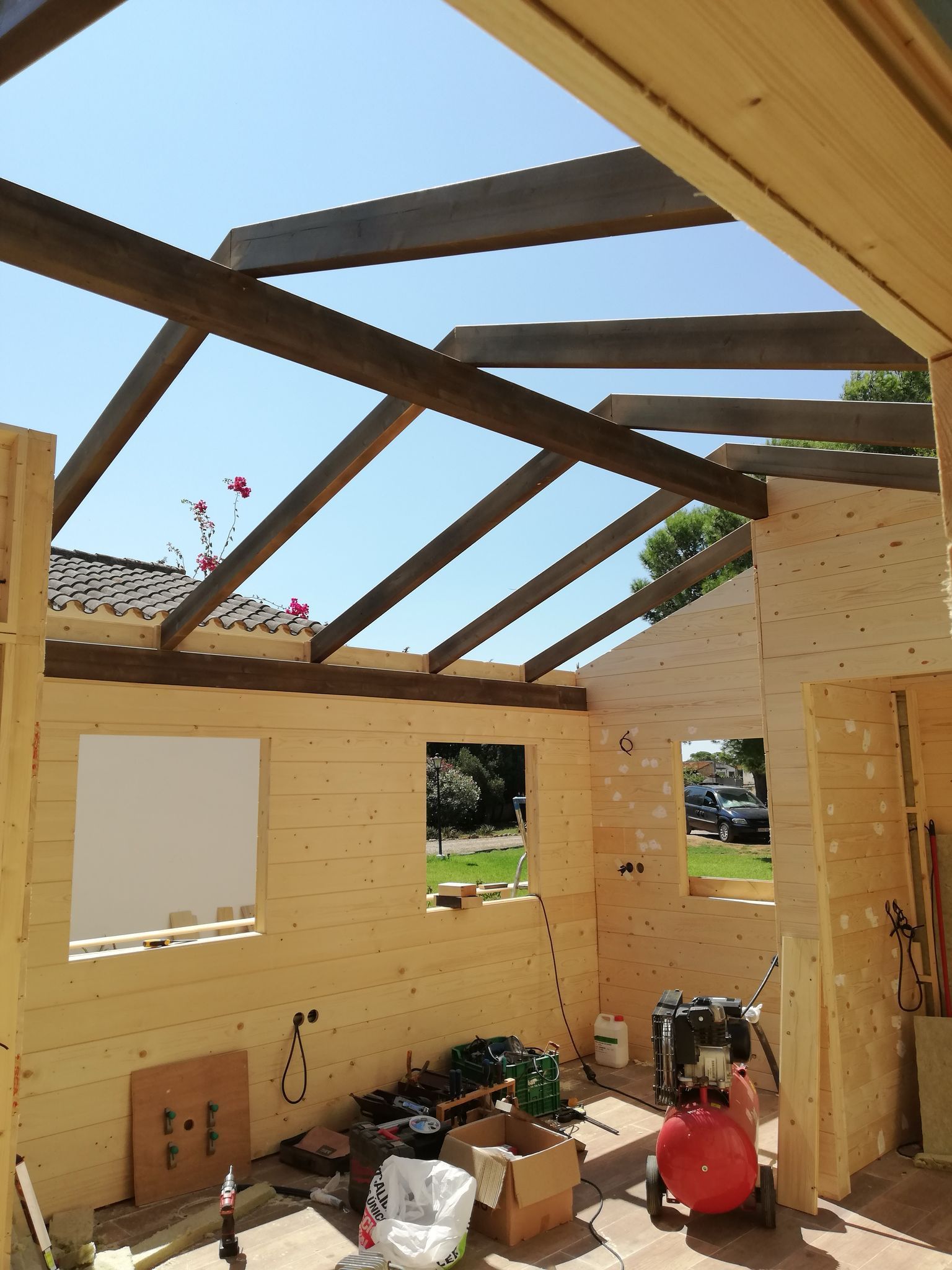 Una casa de madera en construcción con un compresor de aire rojo.