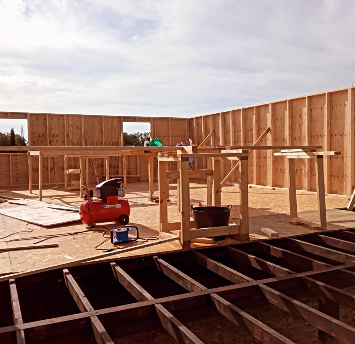 Un compresor de aire rojo se encuentra en el suelo de un edificio en construcción.