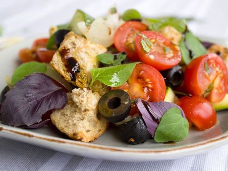 Ein Salat mit Tomaten, Oliven und Croutons auf einem Teller