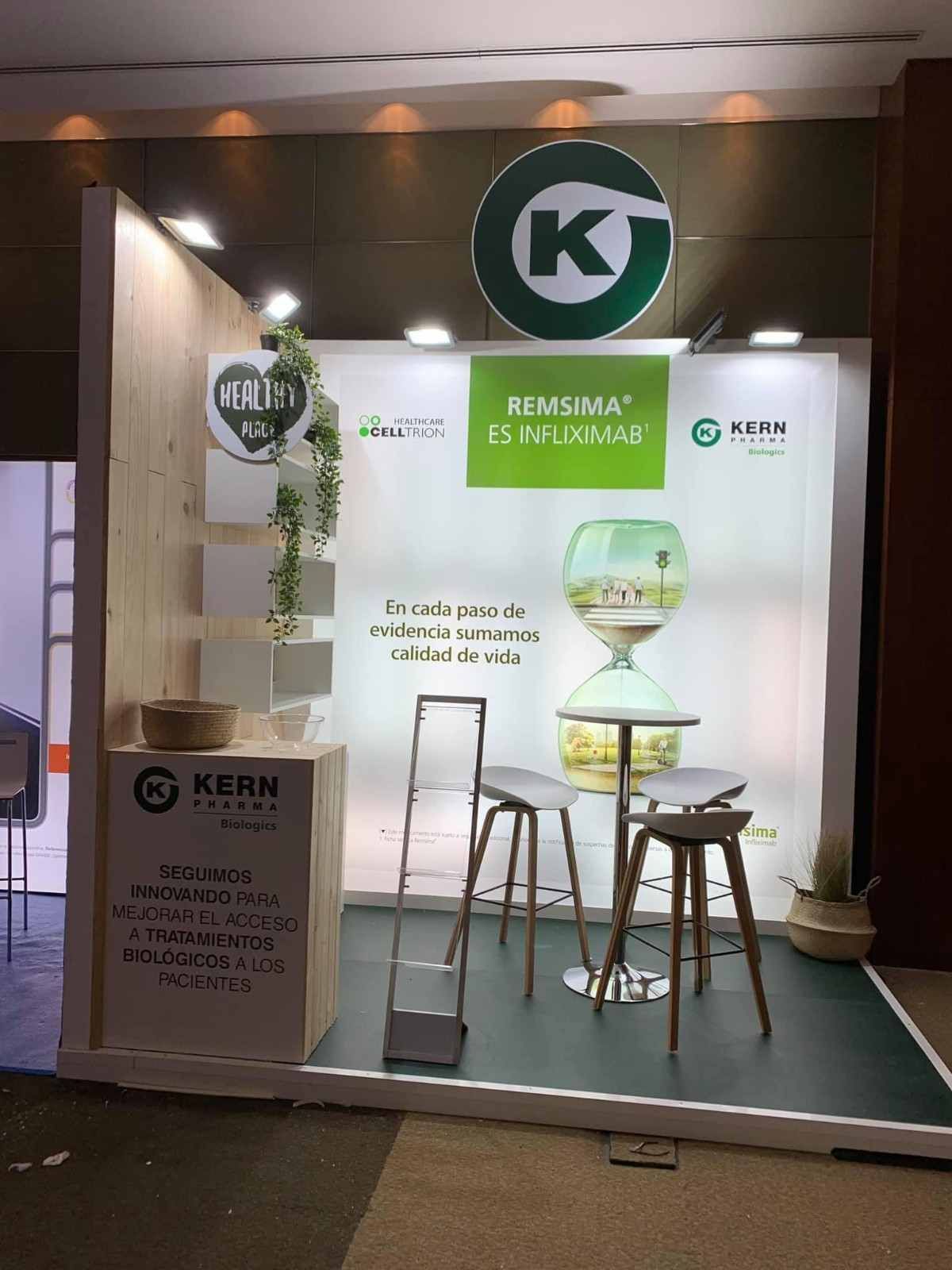 Stand de KERB en una feria, con imagen corporativa en blanco y verde, taburetes de bar y una pequeña mesa redonda a la vista