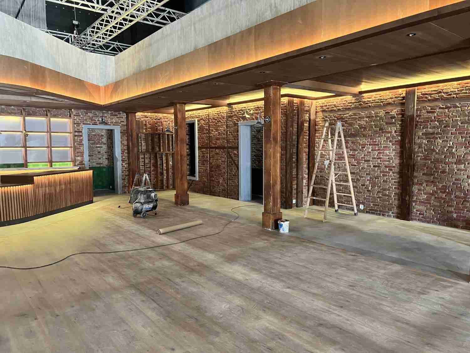 Interior renovado con paredes de ladrillo visto, vigas de madera, una escalera y materiales de construcción en el suelo