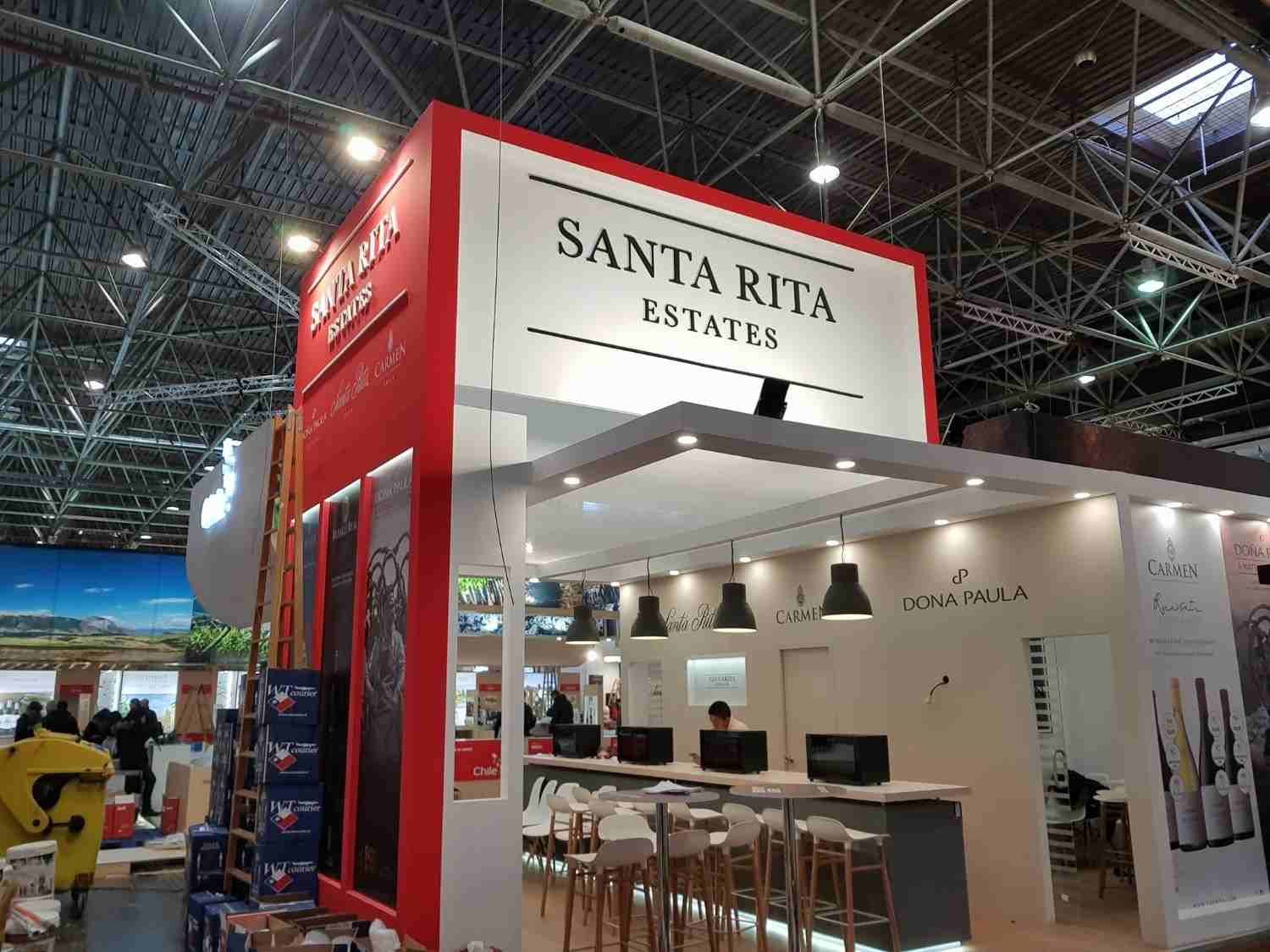 Puesto de vinos de Santa Rita Estates en una feria comercial en interiores, con un letrero rojo y una barra de degustación