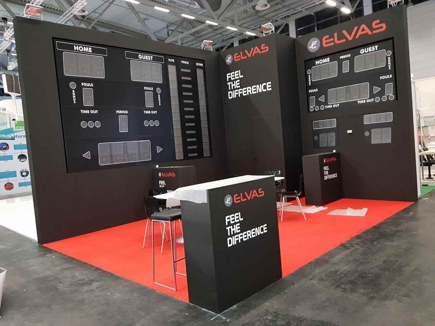 Stand de ELVAS en una feria comercial, con expositores negros y suelo de moqueta roja