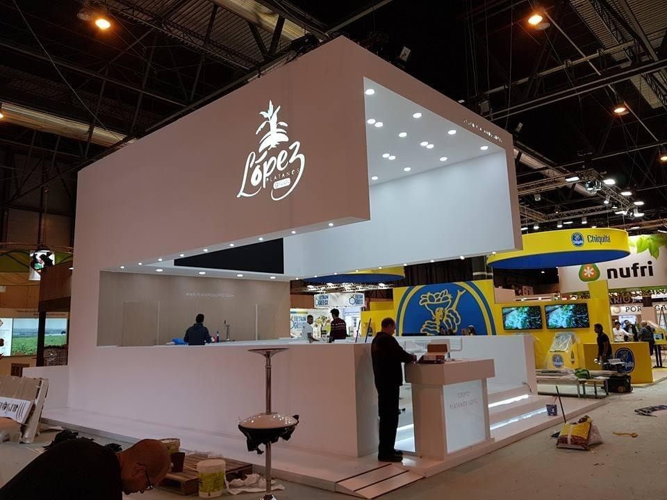 Stand blanco de feria con el logotipo «Lopes» y un mostrador en una exposición cubierta.