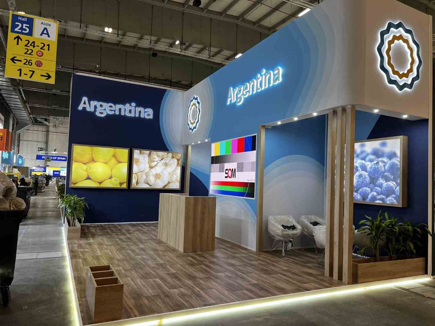 Stand de feria comercial de Argentina con señalización azul, detalles de madera y pantallas en un pabellón de exposiciones