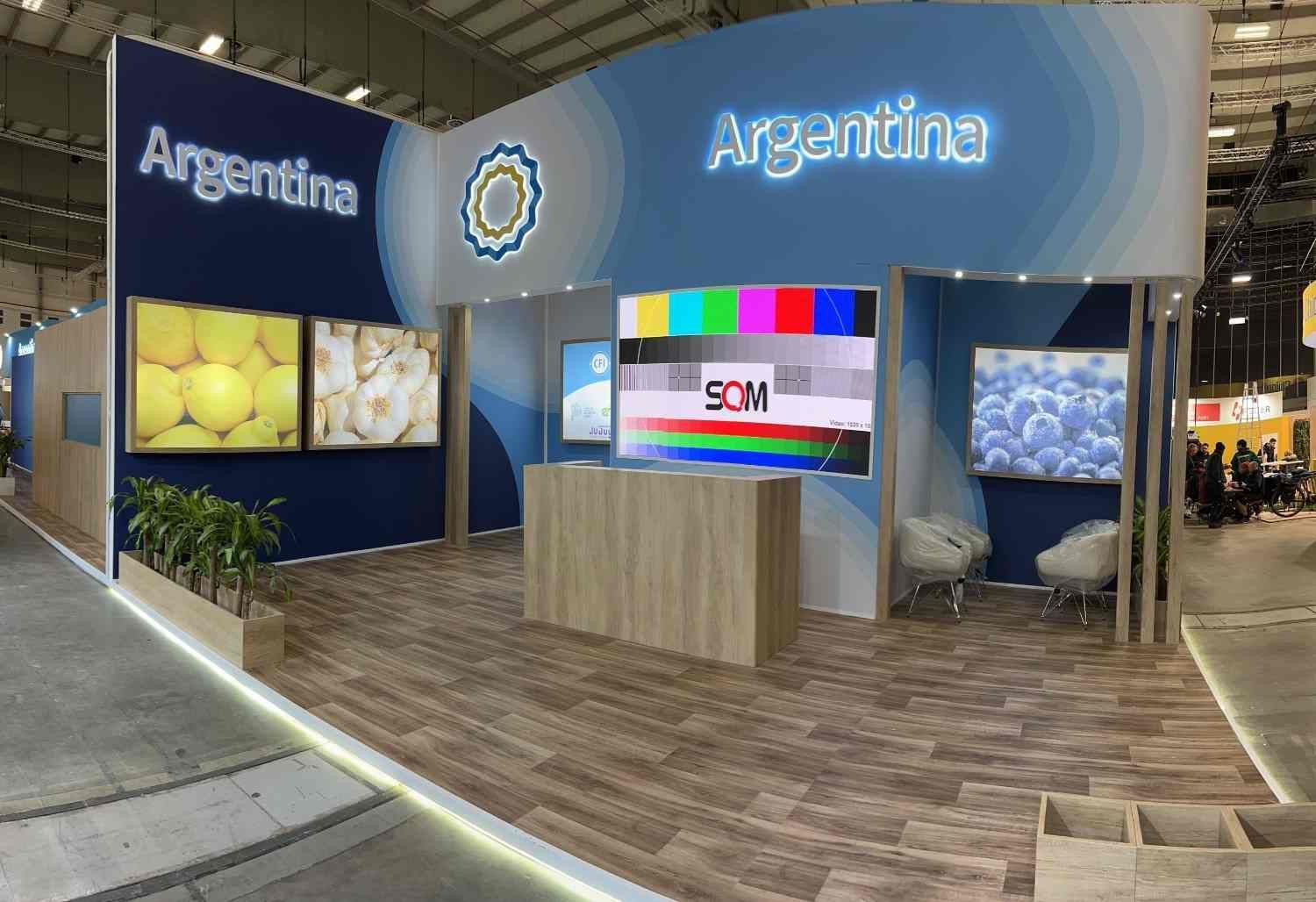 Stand de Argentina con señalización azul, pantallas y suelo de madera en un pabellón de exposiciones