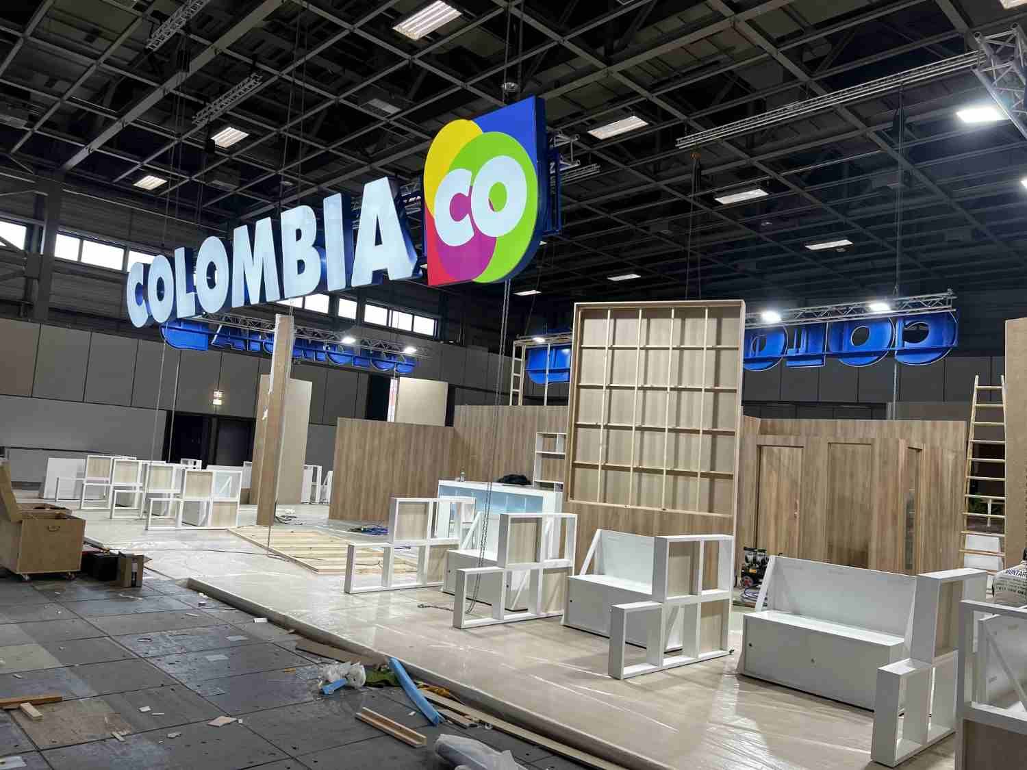 Stand de feria en Colombia en construcción, con mostradores blancos y paneles de madera