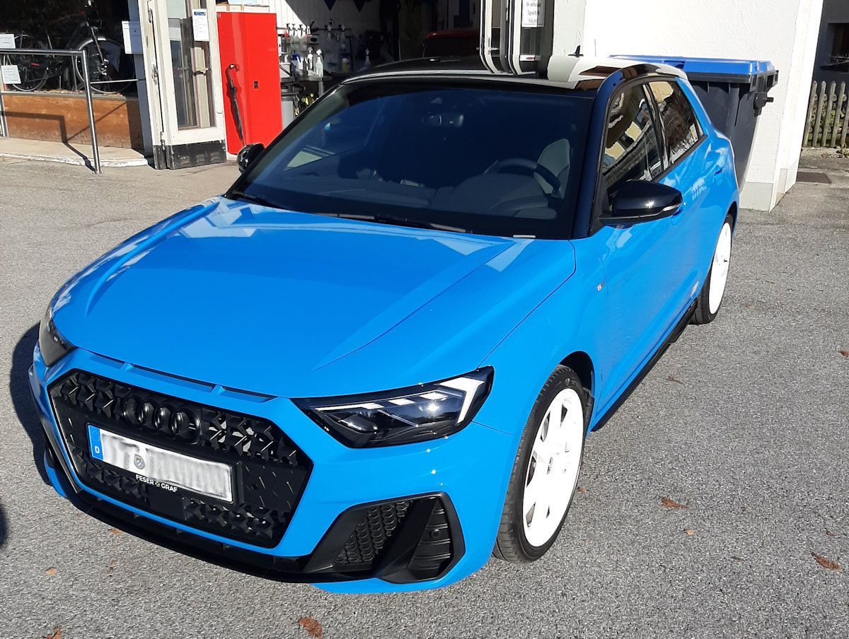 Ein blaues Auto parkt vor einem Gebäude.