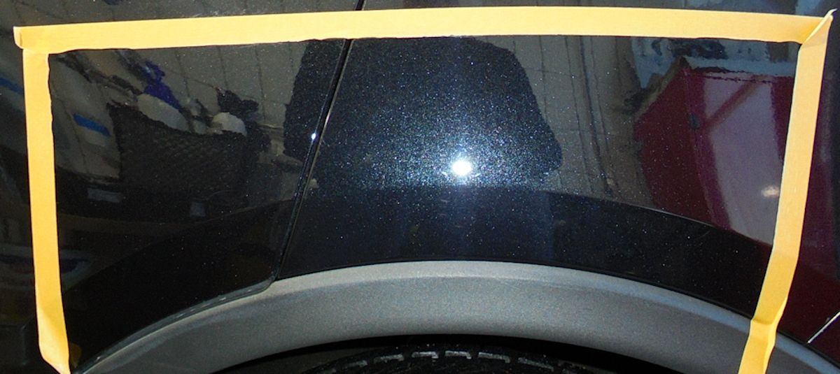 Ein schwarzes Auto mit einem gelben Band darum - mit repariertem Lack