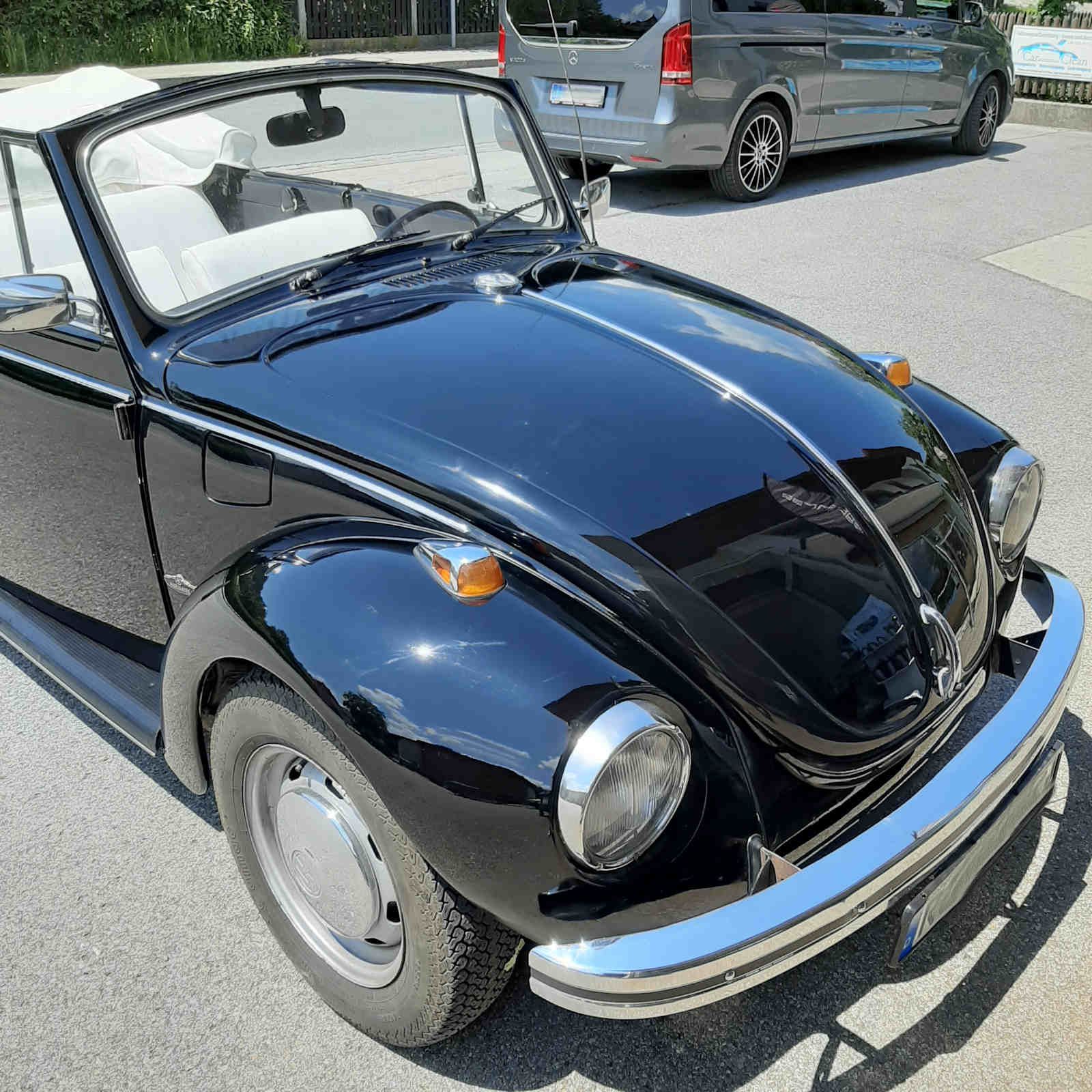 Ein schwarzes Käfer Cabrio steht am Straßenrand