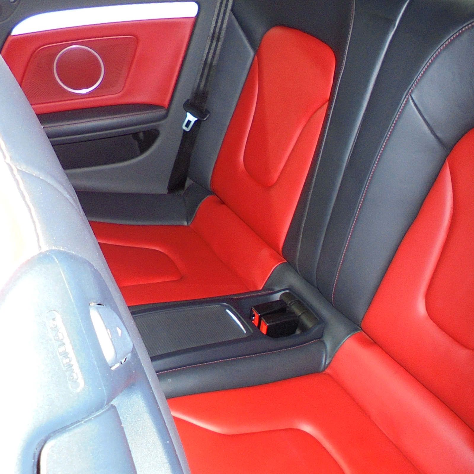 Der Rücksitz eines Autos mit roten und schwarzen Sitzen