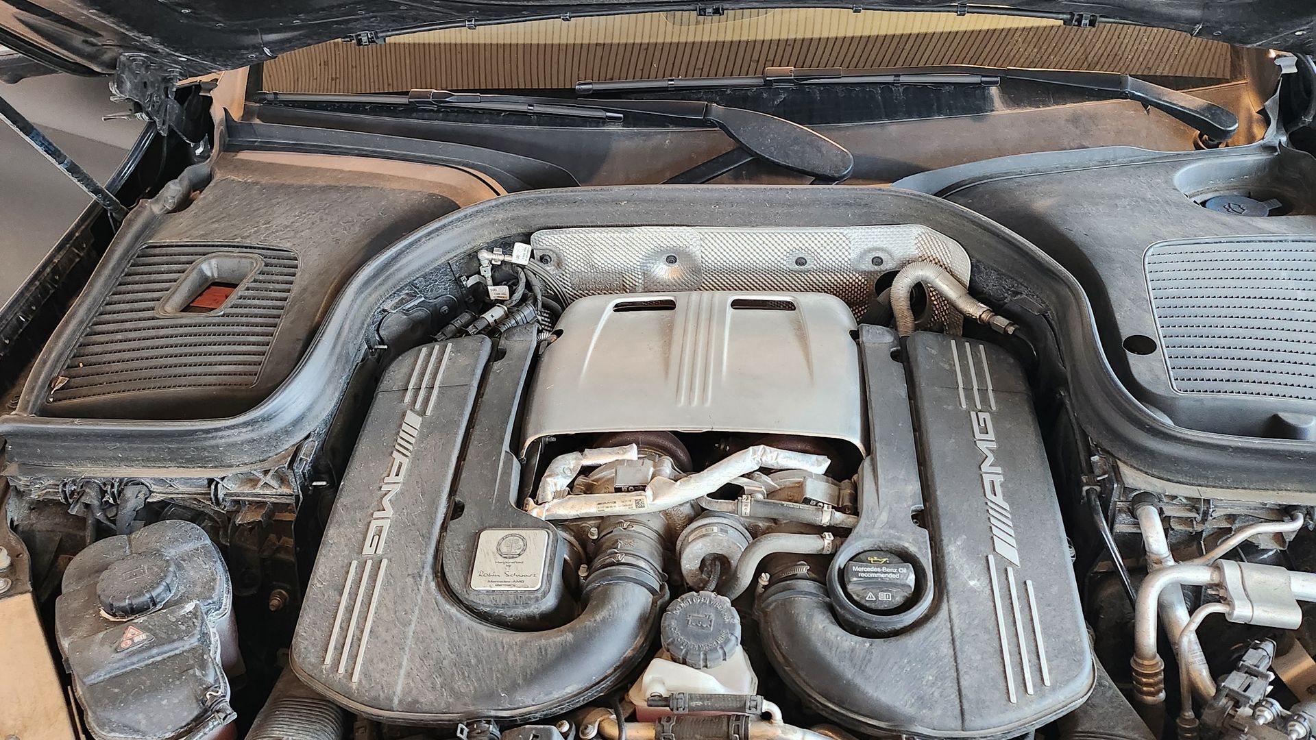 Der Motor eines verschmutzten Mercedes Benz bei geöffneter Motorhaube.