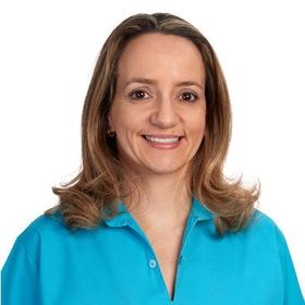 Mulher sorridente, vestindo uma blusa turquesa.