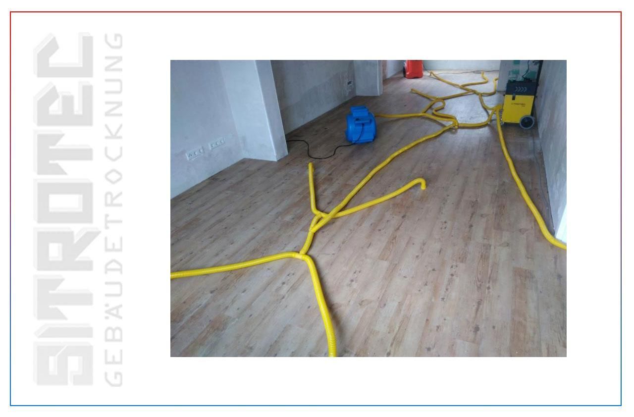 Ein Bild von einem Holzboden, aus dem gelbe Schläuche herauskommen