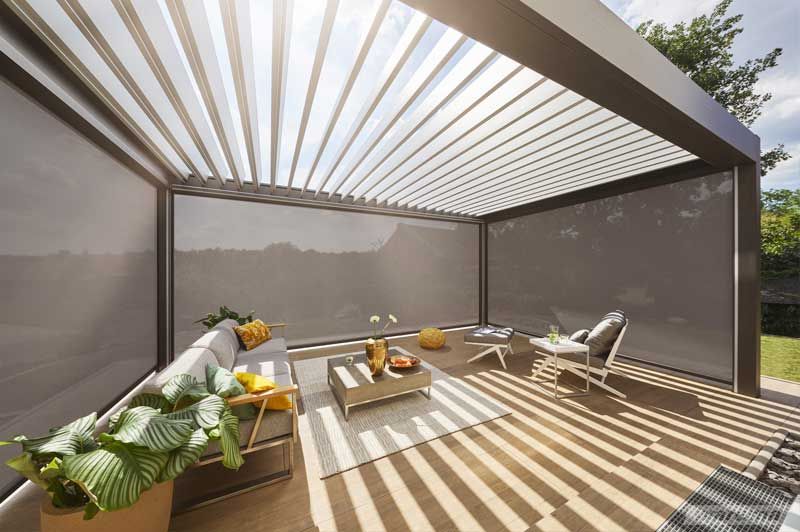 Eine Terrasse mit Pergola und einer Couch und Stühlen darunter.