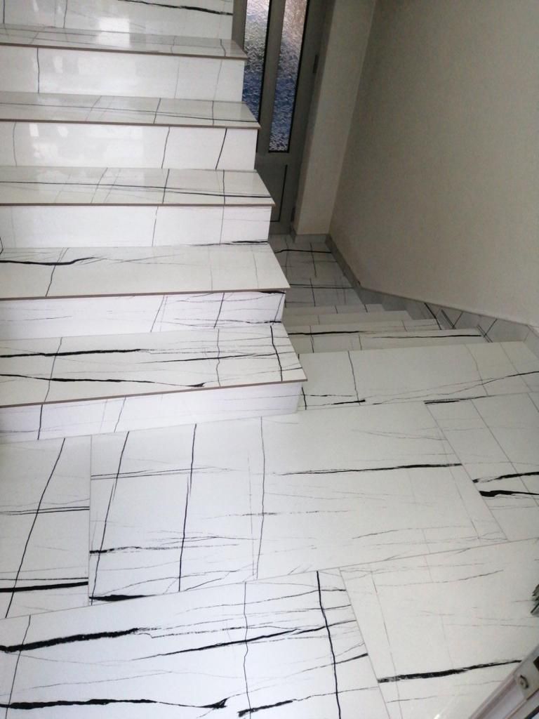 Un ensemble d'escaliers carrelés blancs avec des rayures noires sur le sol.