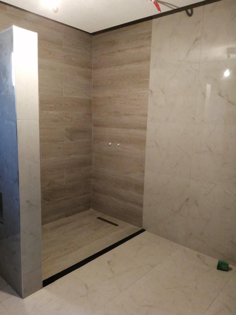 Une salle de bain avec murs carrelés et douche à l'italienne.