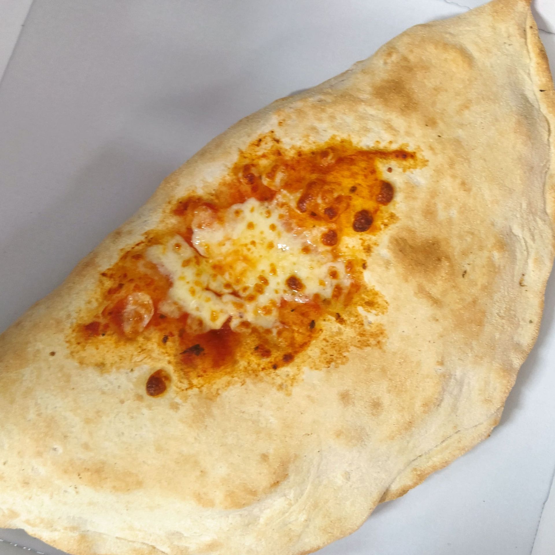 Un primer plano de un calzone relleno de salsa de tomate y queso derretido.