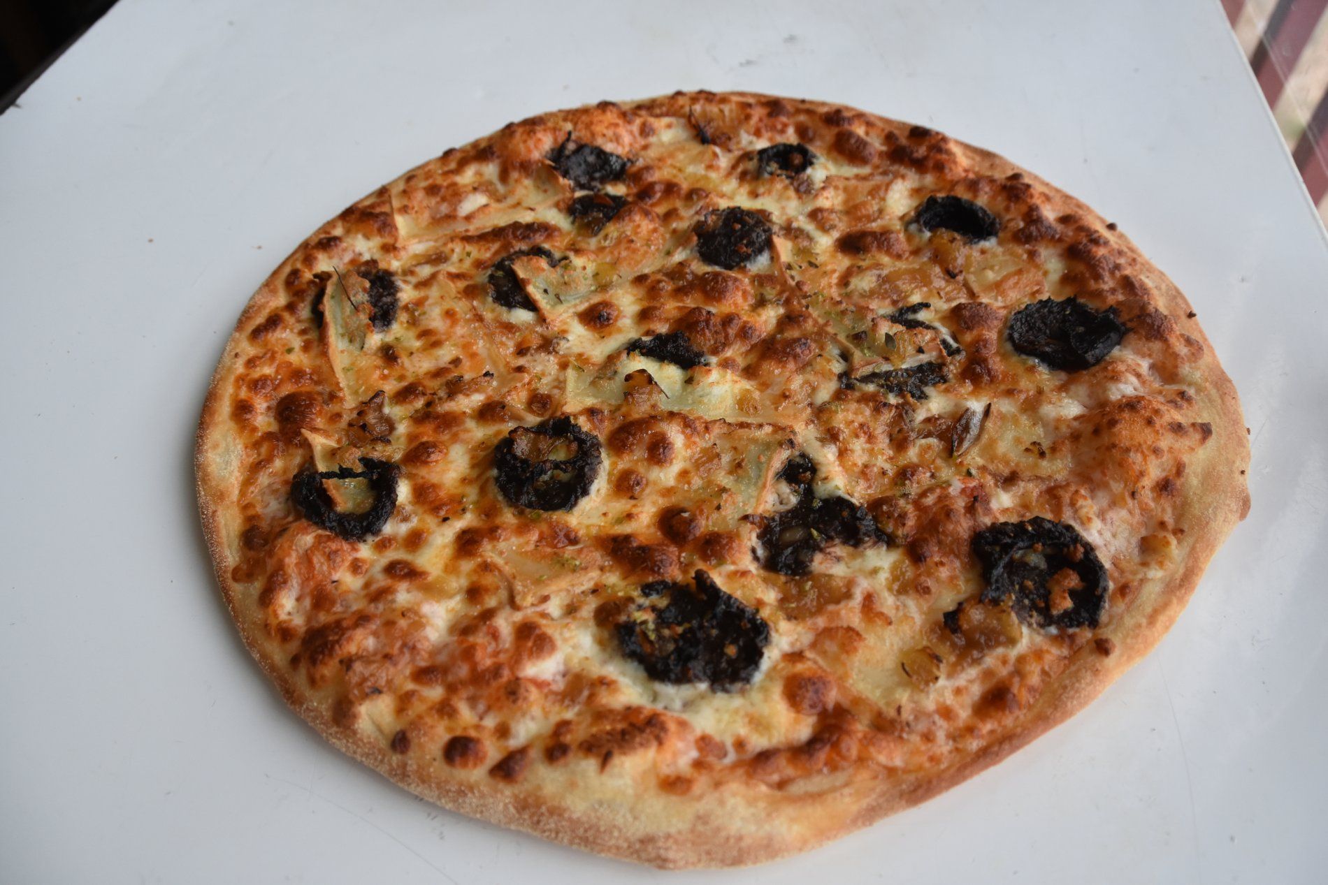 Pizza con ingredientes oscuros y queso derretido en un plato blanco.