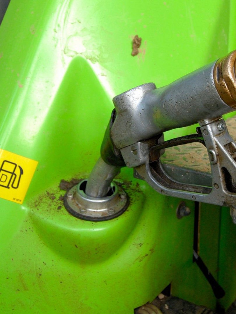 Buse de carburant insérée dans un réservoir vert, prête à être remplie.