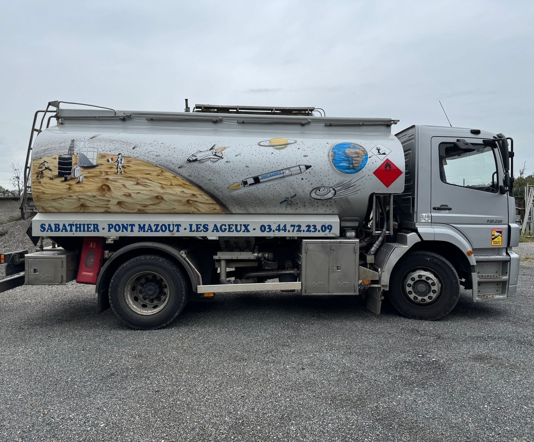 Camion-citerne de Pont Mazout Sabathier. Véhicule gris avec motif peint, texte et plaque de danger.