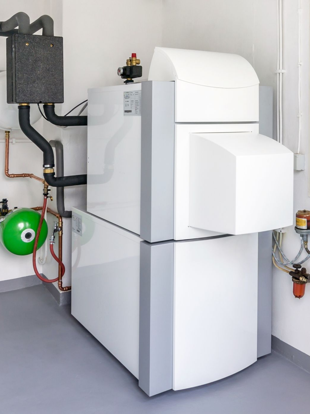 Système de chauffage blanc et gris dans une buanderie, avec tuyaux et réservoir.