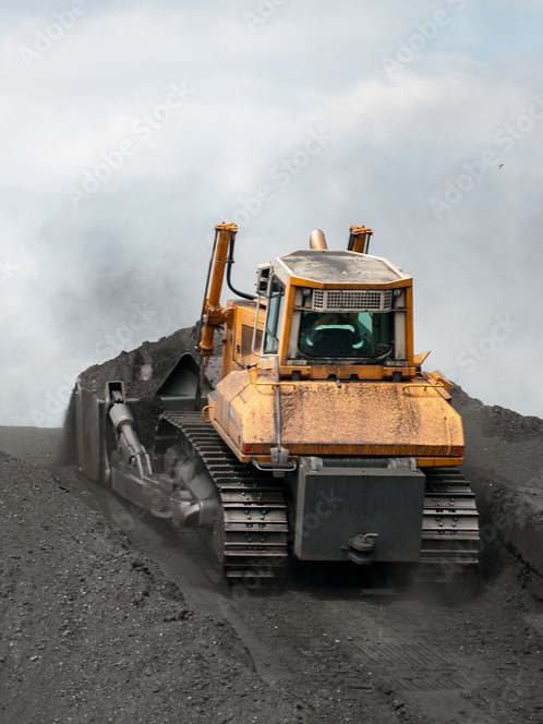 Un bulldozer jaune pousse de la terre gris foncé.