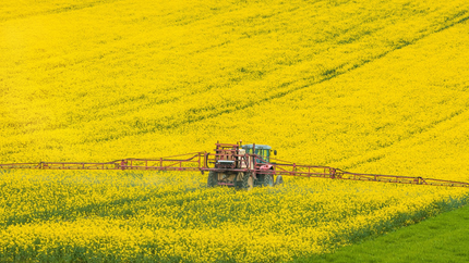 Une voiture blanche en train d'être ravitaillée avec une pompe à essence verte bio.