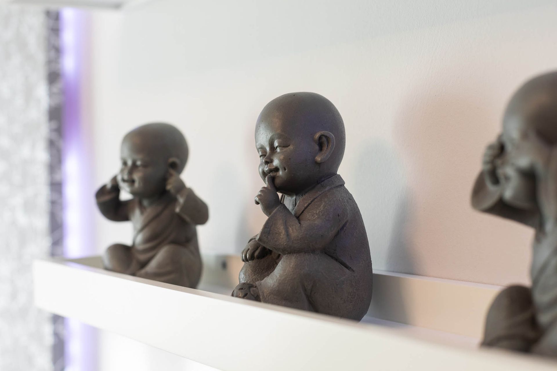 Drei Buddhastatuen stehen auf einem weißen Regal.