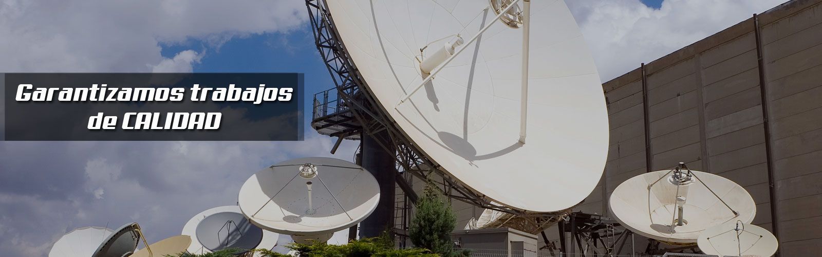 Un montón de antenas parabólicas están situadas delante de un edificio.