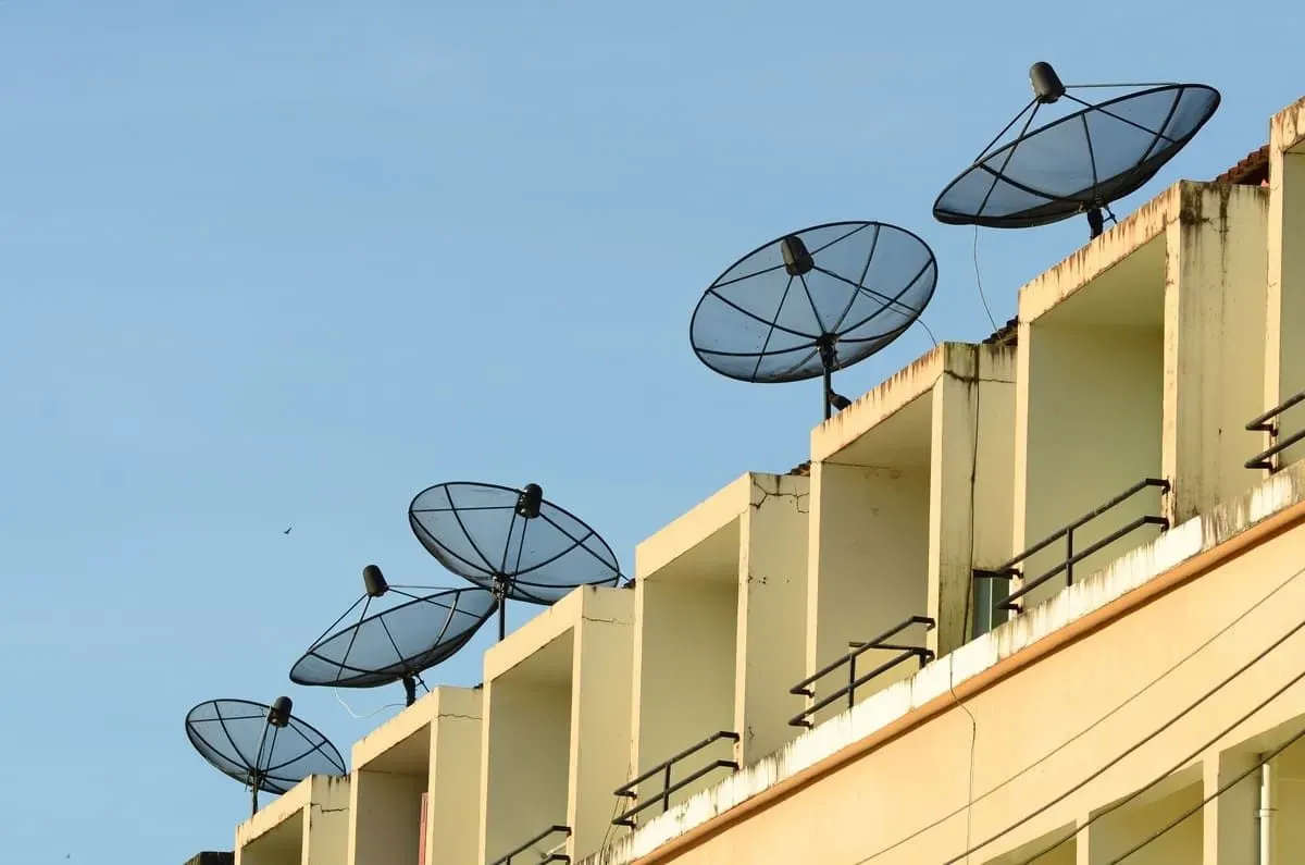 Una fila de antenas parabólicas en la parte superior de un edificio.