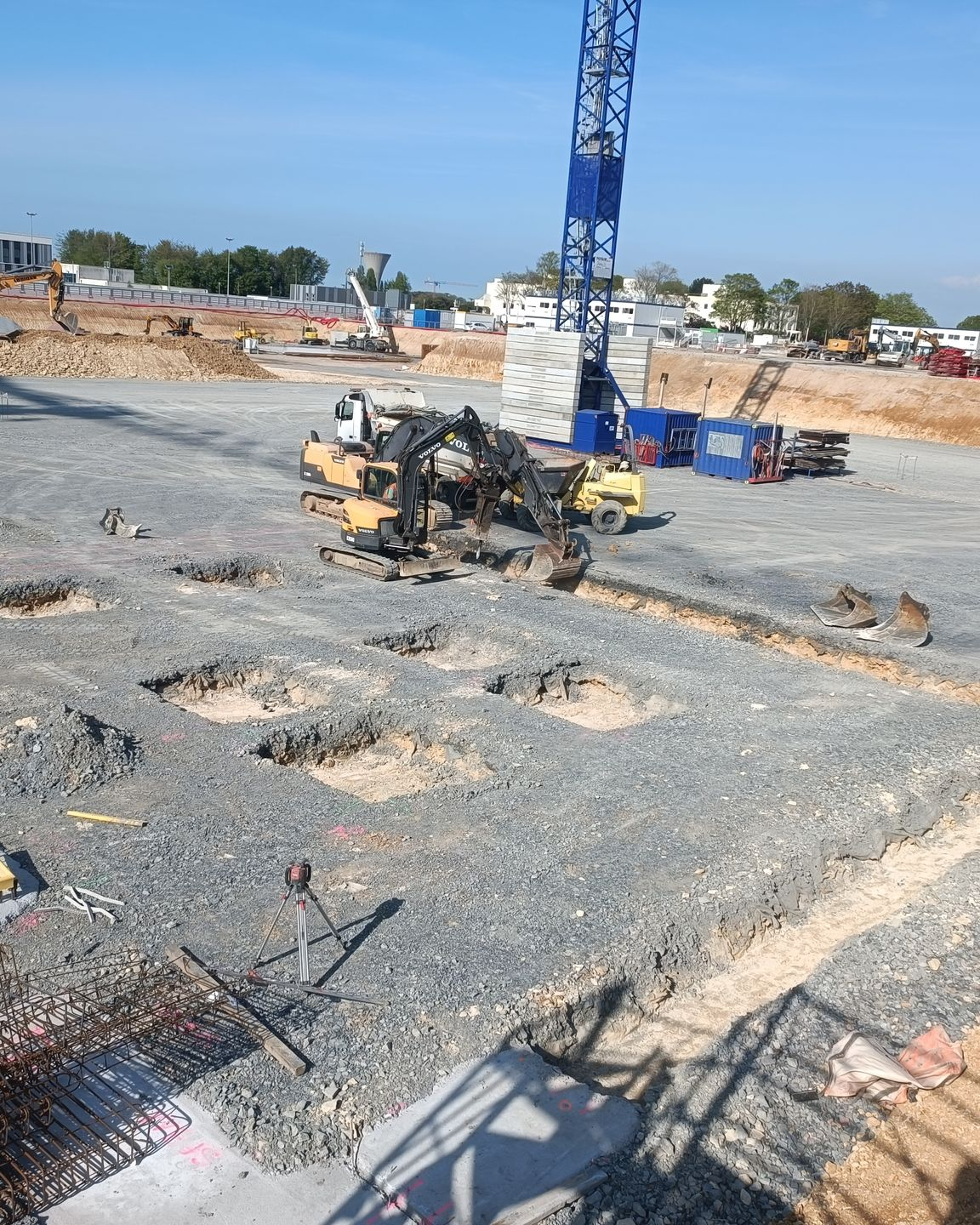 Grand chantier de gros œuvre avec une grue bleue au centre