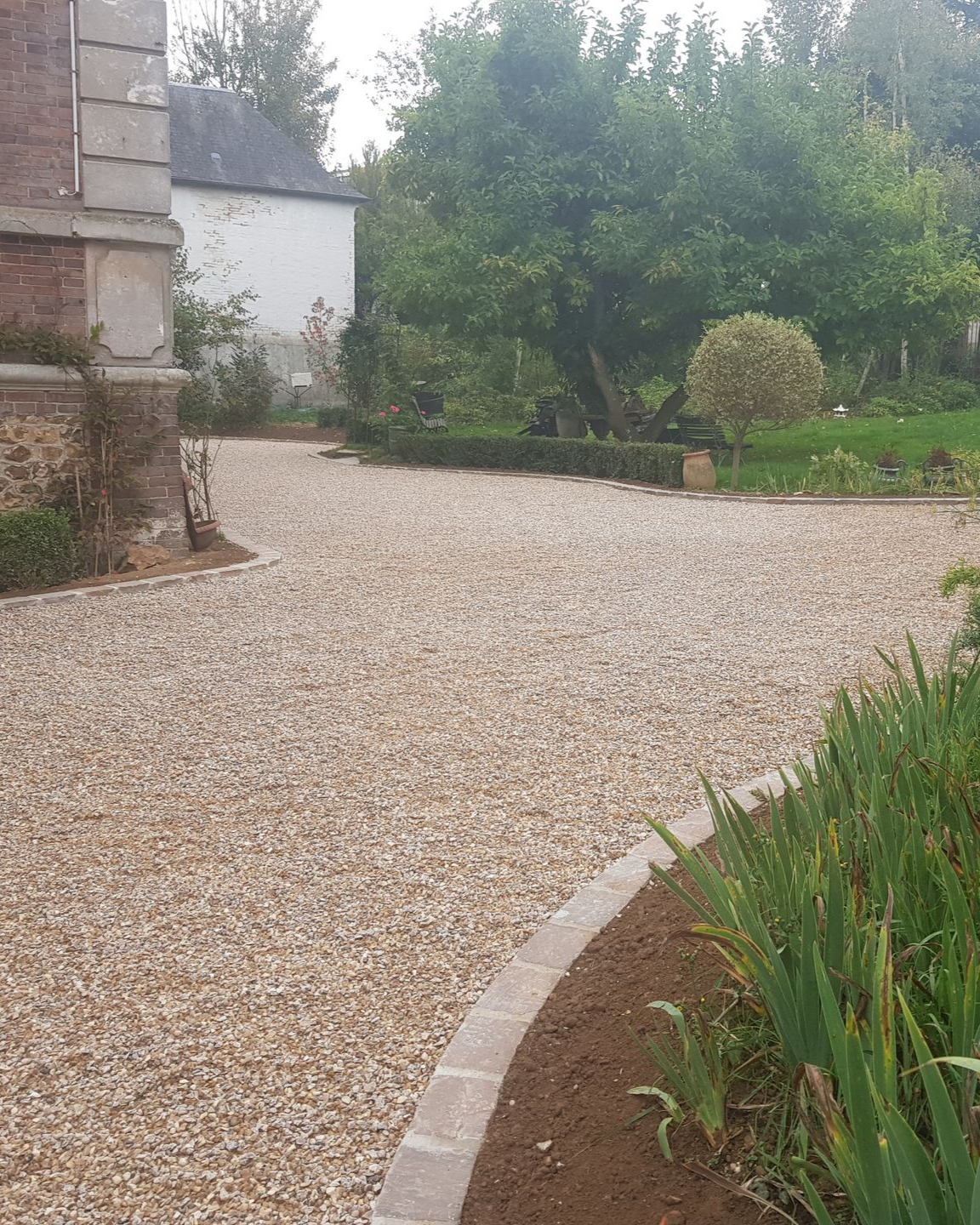 Allée en gravier entre un jardin et une maison