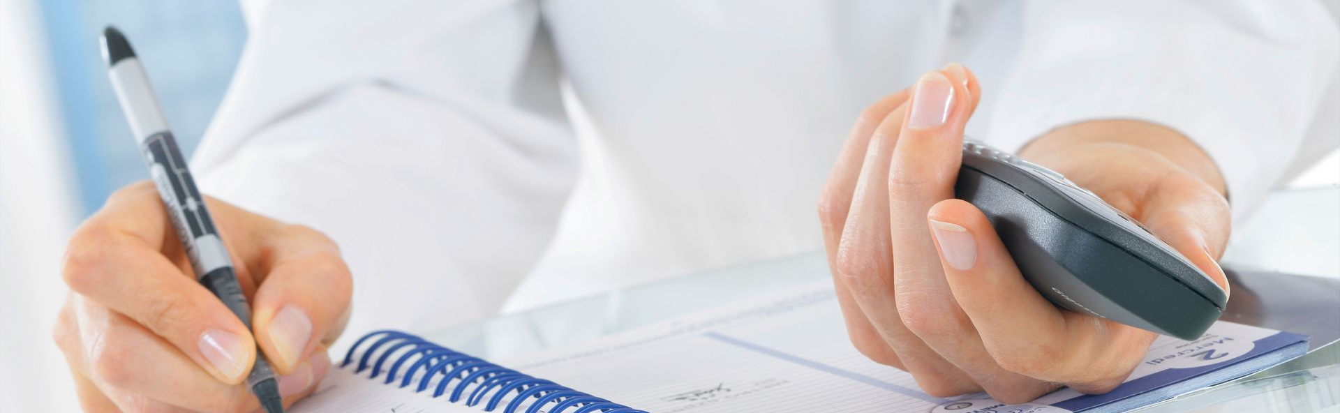 Une pesonne est en train d'écrire portant un téléphone  dans l'autre main