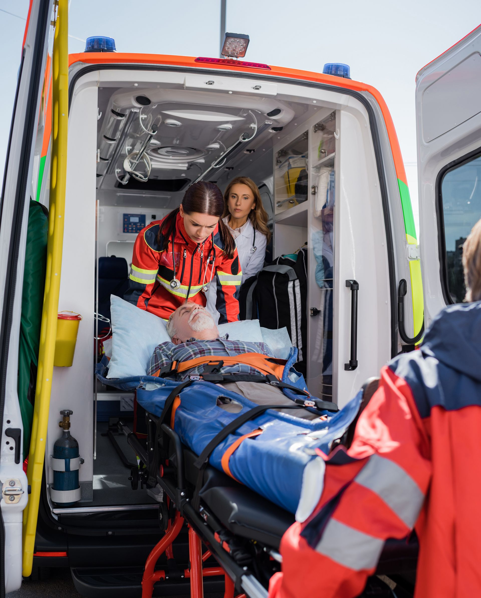 Des personnes montent un monsieur allongé sur le brancard dans l'ambulance