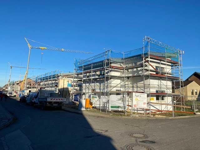 Ein im Bau befindliches Gebäude mit Gerüst und einem Kran im Hintergrund.