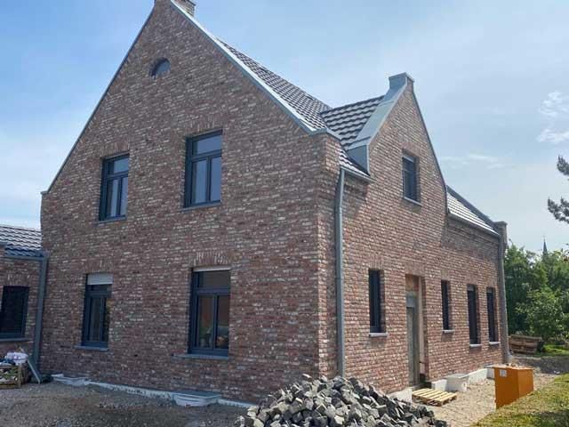 Es entsteht ein großes Backsteinhaus mit vielen Fenstern.