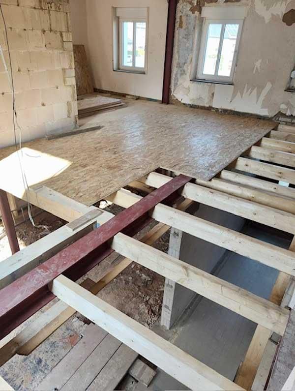 Ein im Rohbau befindlicher Raum mit Holzbalken und Holzboden.