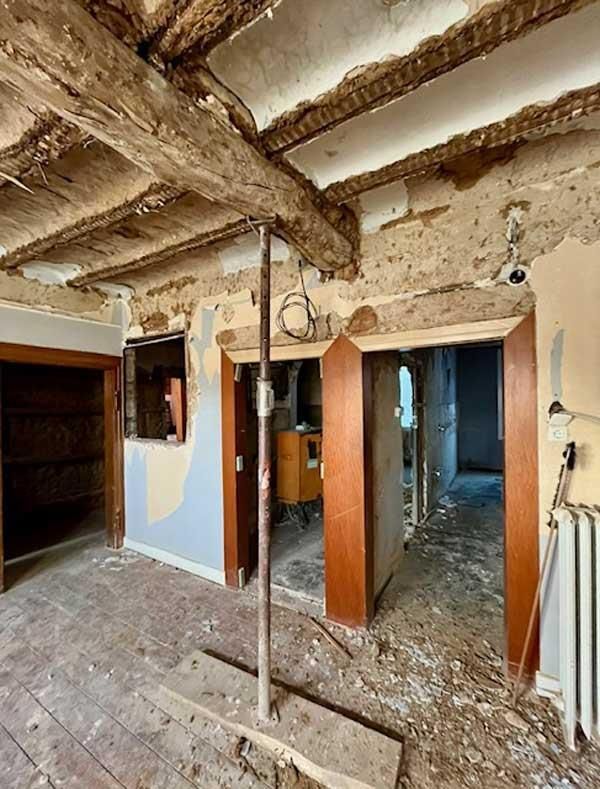 Ein Raum mit Holzbalken und Ziegelboden wird umgebaut.