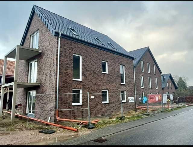 Ein Backsteingebäude mit Zaun darum ist im Bau.