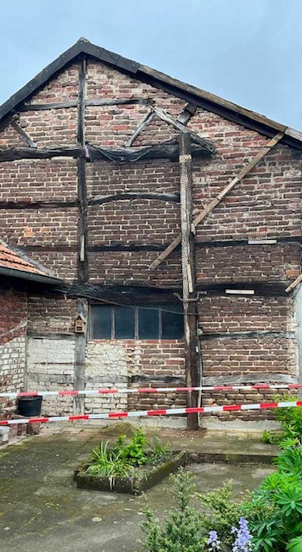 Ein großes Backsteingebäude mit Holzdach wird abgerissen.