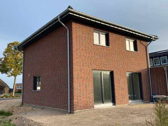 Ein rotes Backsteinhaus mit Glasschiebetüren und Fenstern.