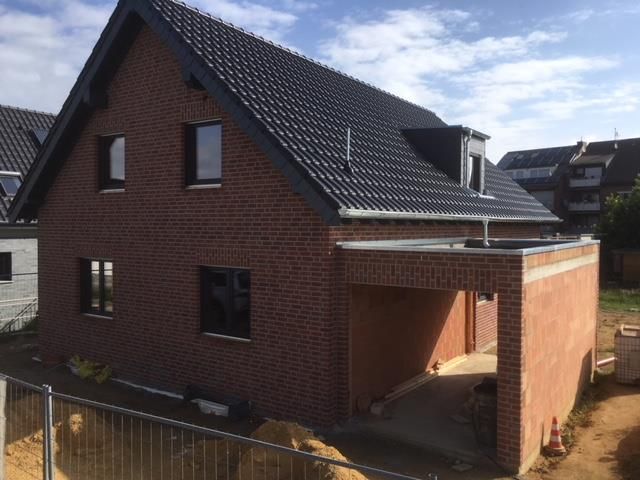 Ein Backsteinhaus mit schwarzem Dach ist im Bau