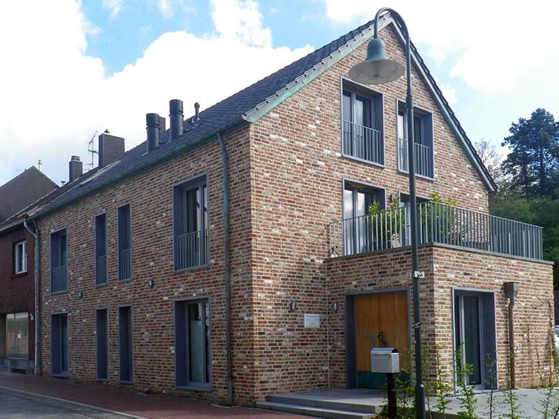 Ein großes Backsteingebäude mit einem Balkon und einer Straßenlaterne davor.