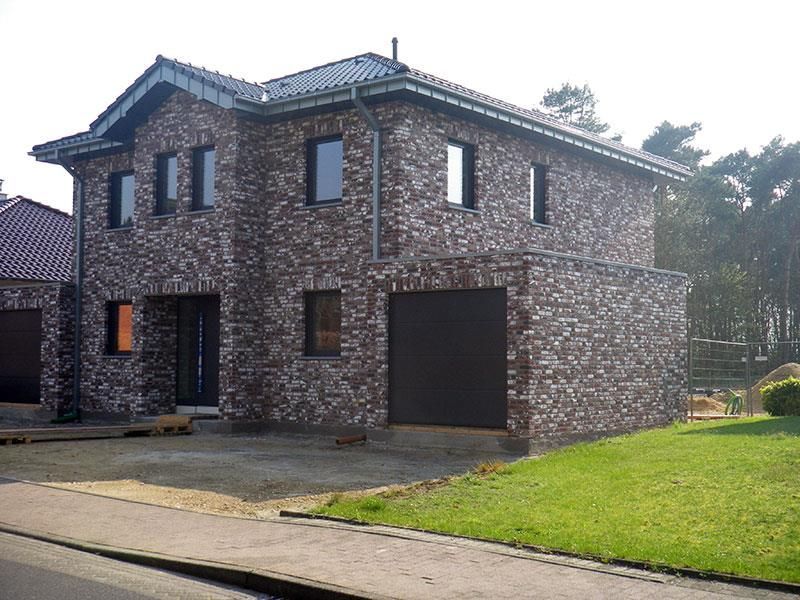 Ein großes Backsteinhaus mit einem schwarzen Garagentor