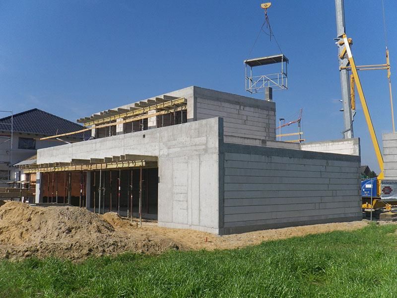 Auf einem Feld wird ein Haus gebaut, im Hintergrund ist ein Kran zu sehen.