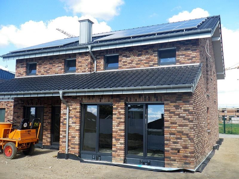 Es entsteht ein Backsteinhaus mit Sonnenkollektoren auf dem Dach.