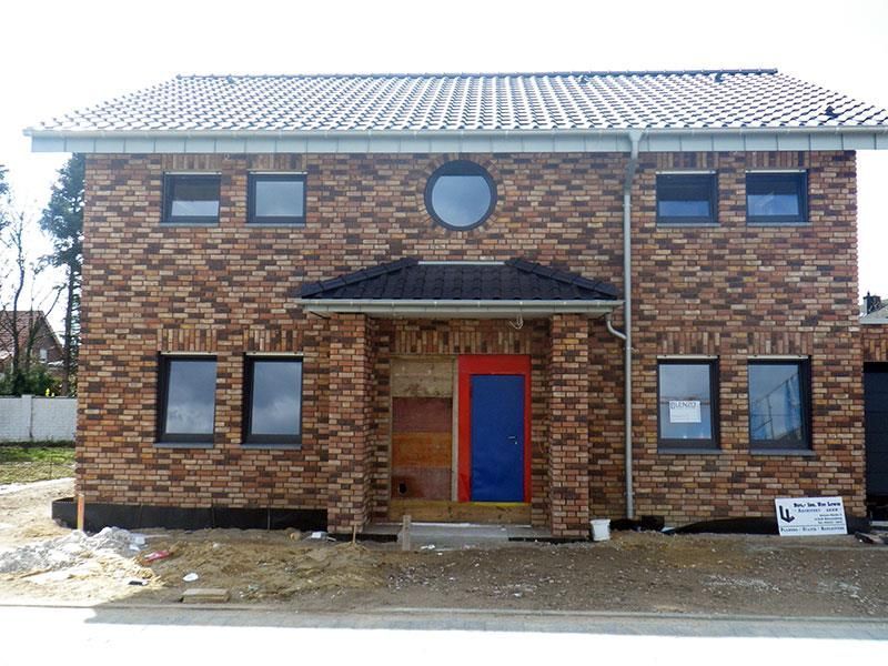 Ein Backsteinhaus mit einer blauen Tür und einem runden Fenster