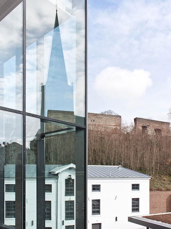 Ein Kirchturm spiegelt sich in den Fenstern eines Gebäudes